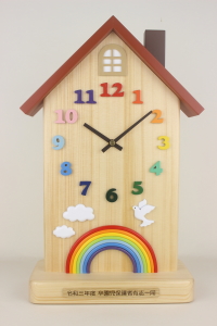  alt="卒園記念品：「虹と雲とハト」をお入れした家の形の置き時計"